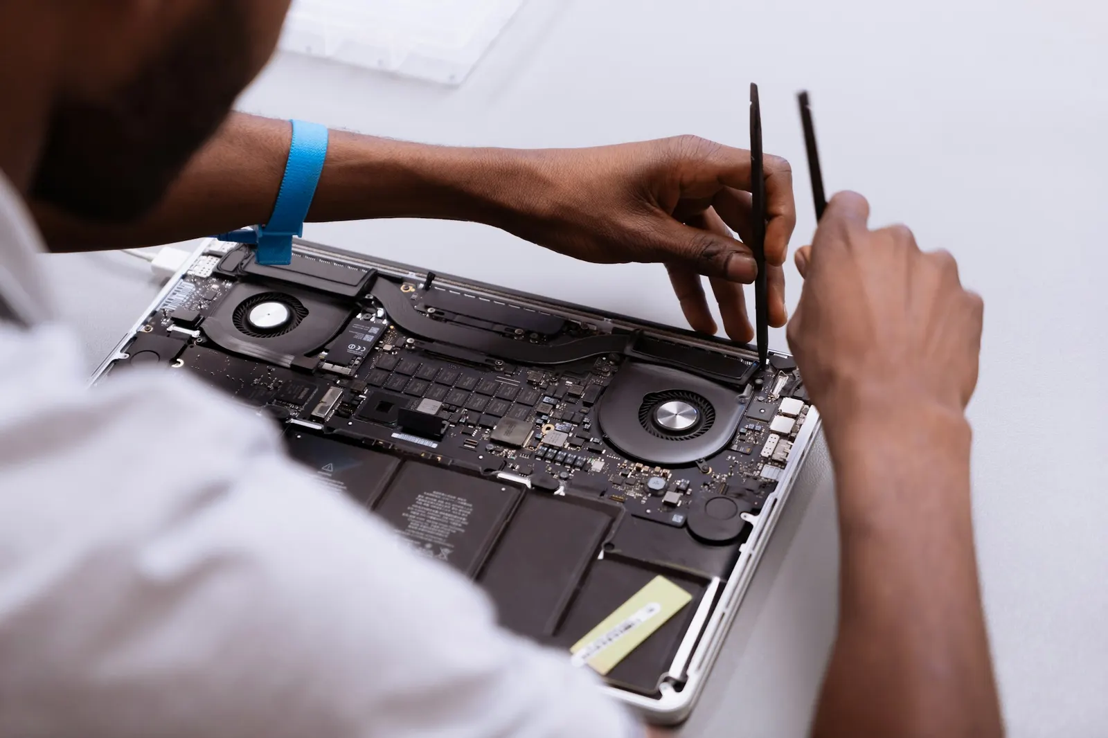 Técnico abrindo um notebook na bancada, com os coolers e a placa à mostra
